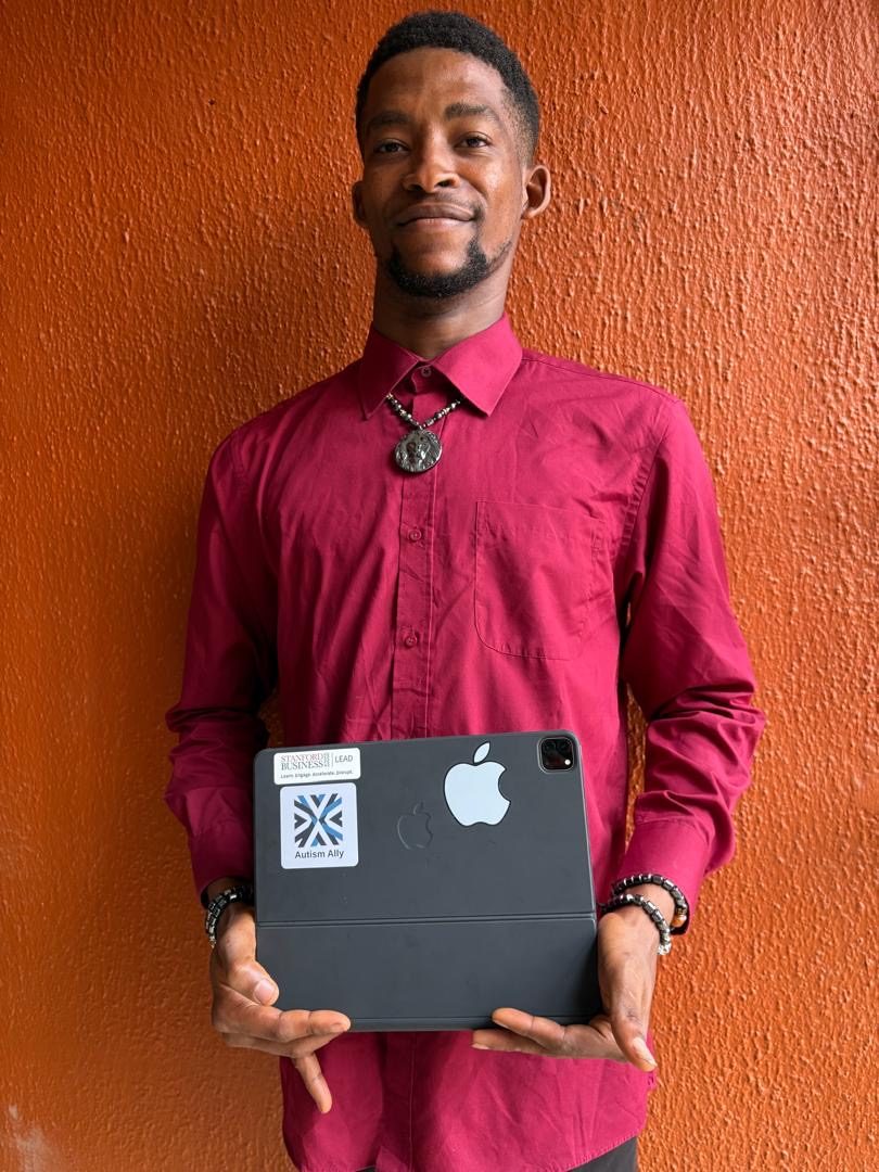 Kosi from Anambra State holding a device with an Autism Ally sticker.