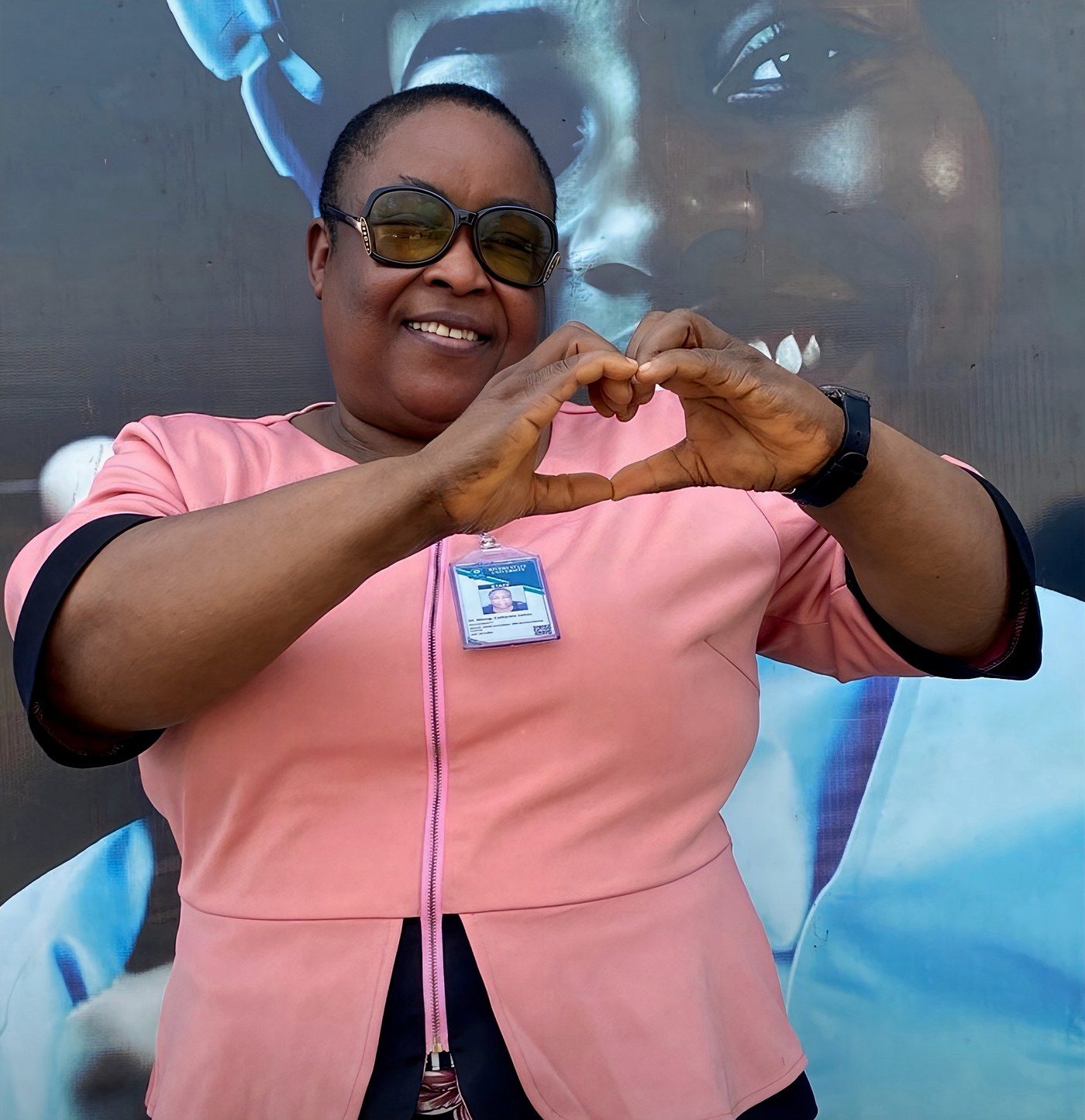 Dr. Catherine James Atteng, National President of the Nigeria Association of Special Education Teachers, forming a heart shape with her hands in the sign of autism inclusion.