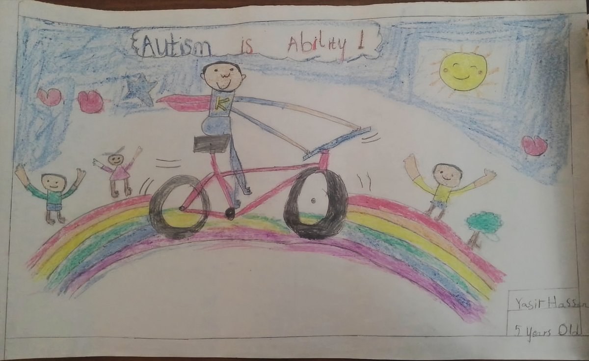 Yasir Hassan, age 5, Spark a Spectrum 2026 Art Competition First Place winner in Category A. His artwork shows Superhero Kanye riding a bicycle on a rainbow road with friends cheering him on. The caption reads: Autism is Ability.